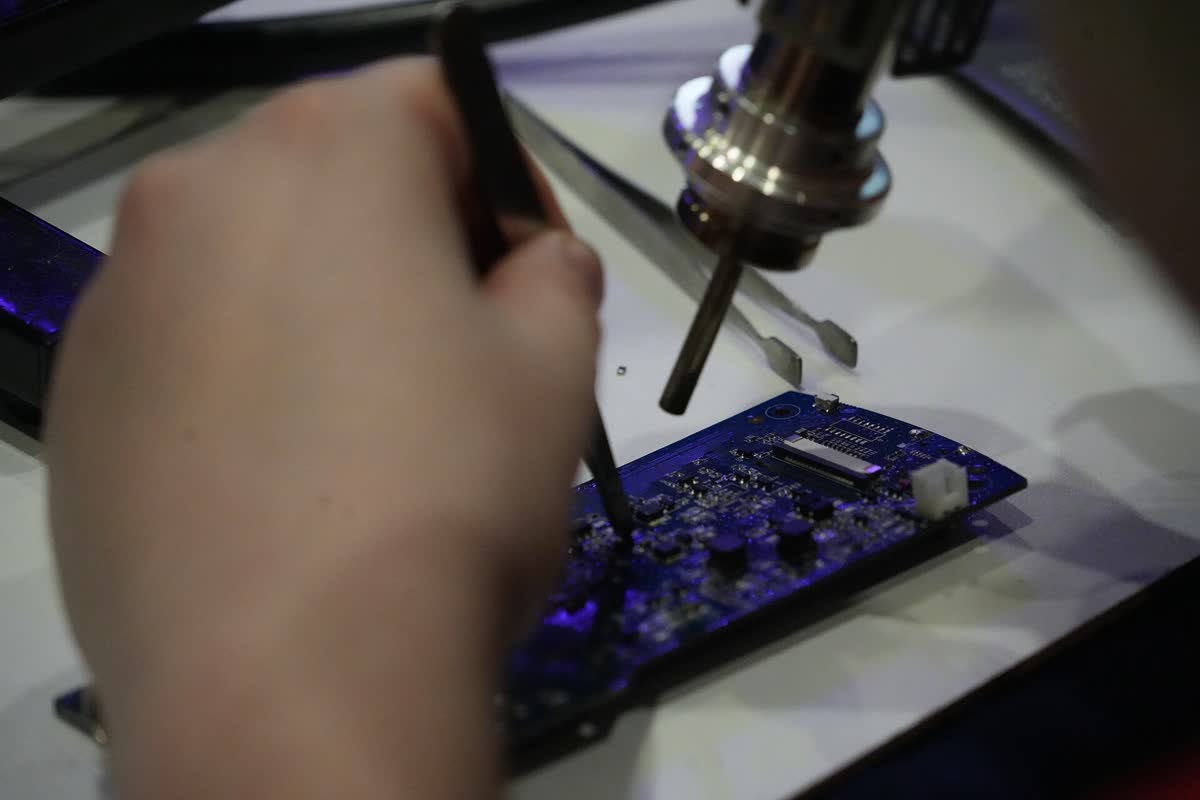 Hands soldering a circuit board under a magnifier
